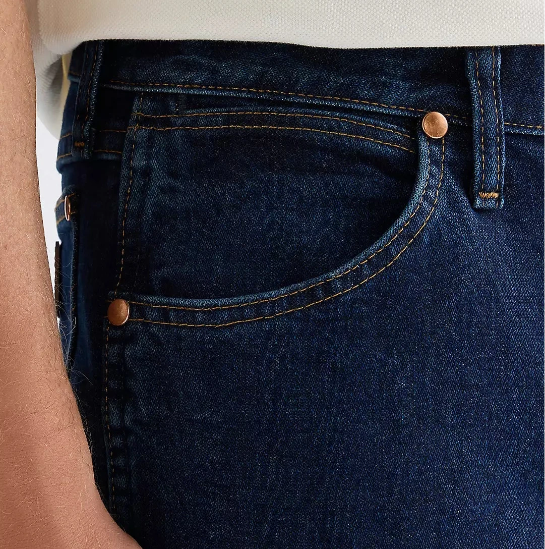 Close-up of dark blue jeans with a person's hand on a light gray background