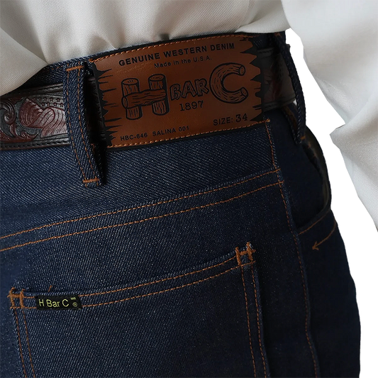 Close-up of blue jeans with a H Bar C belt and label.
