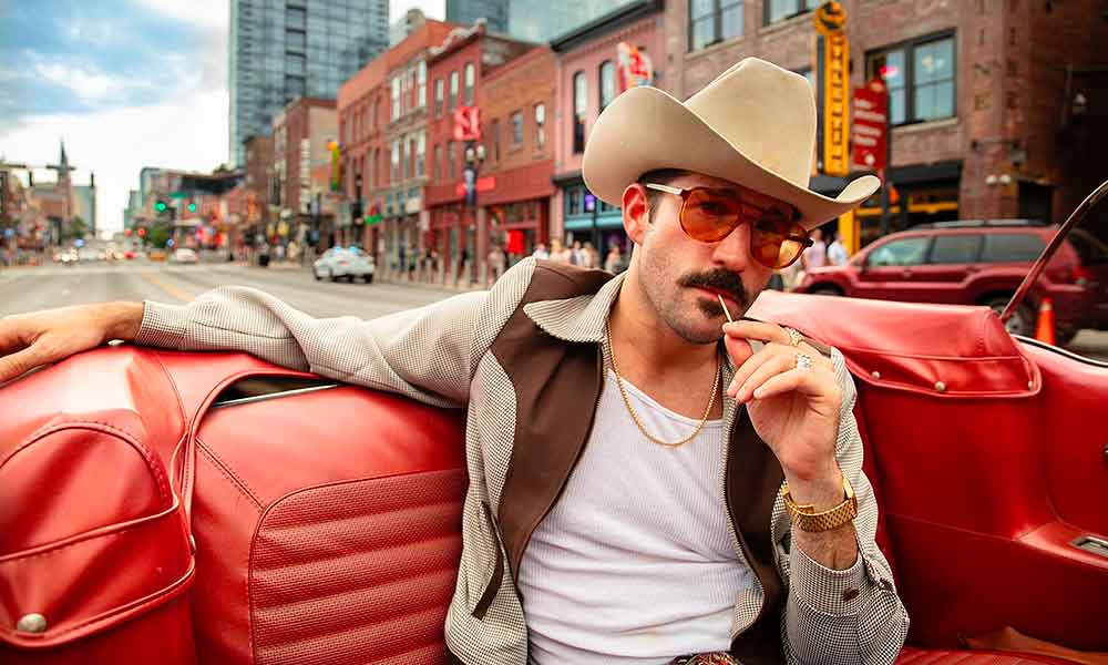 Man wearing a jacket, sitting in the back seat of a car
