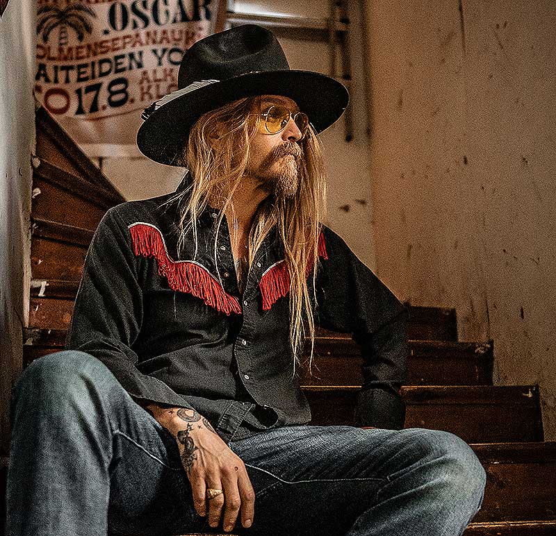 Man wearing vintage western wear like a western hat, western shirt, and jeans.