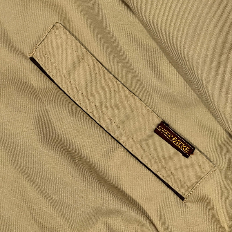 Close-up of beige fabric with a brand label on a pocket