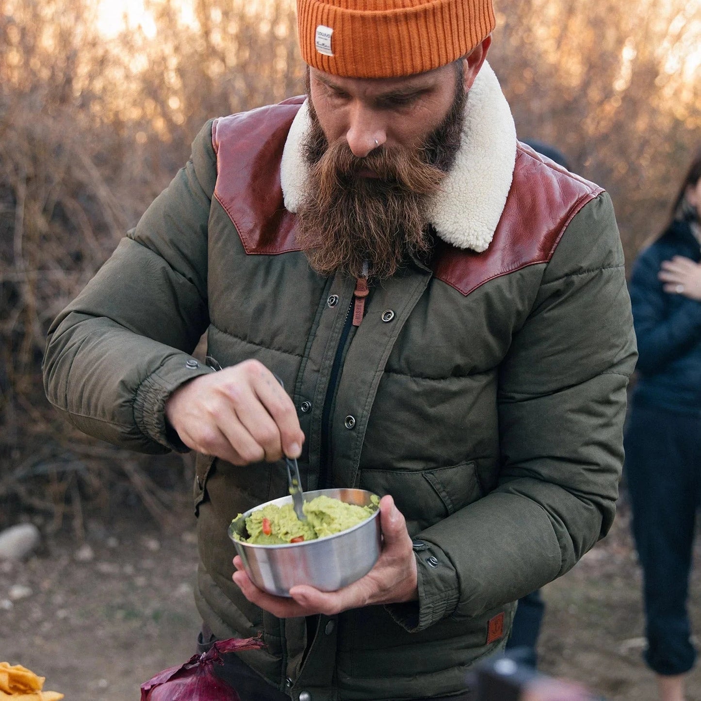 A man is doing camping chores wearing an olive colour Iron And Resin Basin Jacket. 