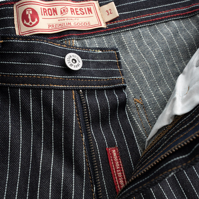 Close-up of a denim garment with 'Iron and Resin' label and pinstripe pattern.