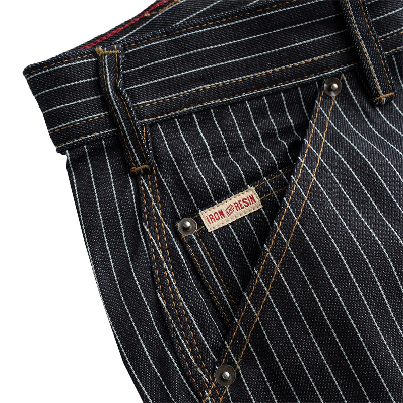 Close-up of black pinstripe jeans with a brand label