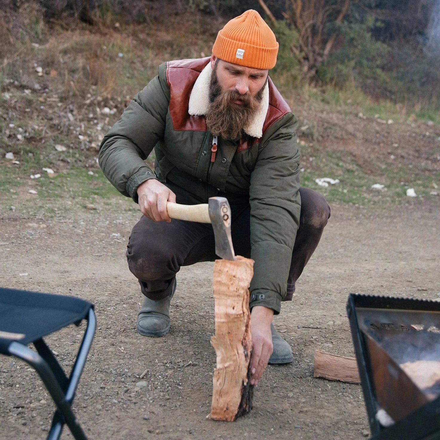 Man making firewood wearing Iron & Resin’s Basin Jacket. 