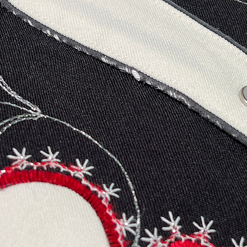 Close-up of embroidered fabric with red and white patterns on a black background