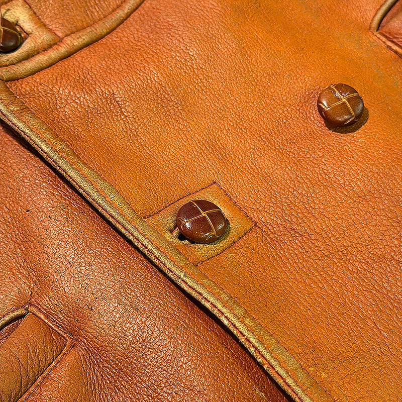 Close-up of a brown leather jacket with button details