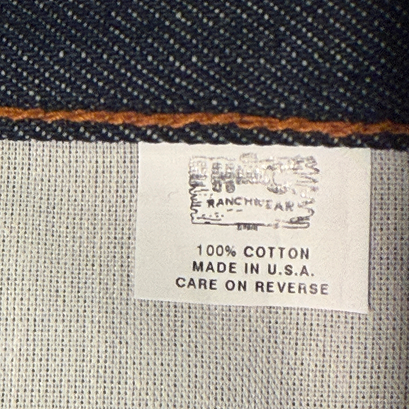 Fabric label on a piece of clothing with text and a H Bar C logo.