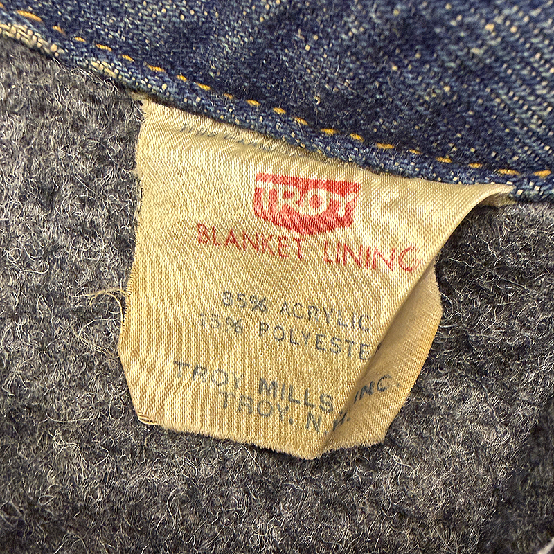 Label on a garment with 'Troy' branding and text about blanket lining composition.