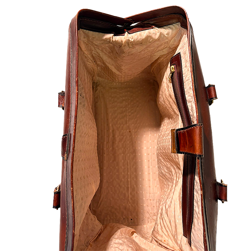 Close-up of the open interior of a brown leather bag or case, showing a tan textured lining and dark brown zipper details.