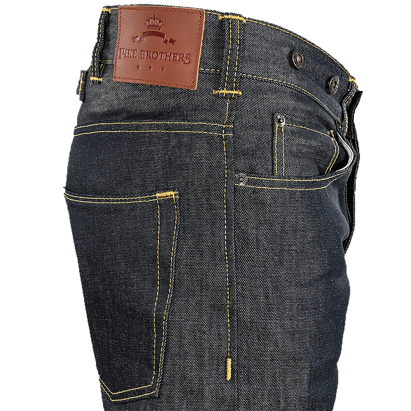 Close-up of the back waistband and pockets of dark indigo denim jeans, showing a brown leather patch with the embossed brand name 'Pike Brothers' and yellow contrast stitching.