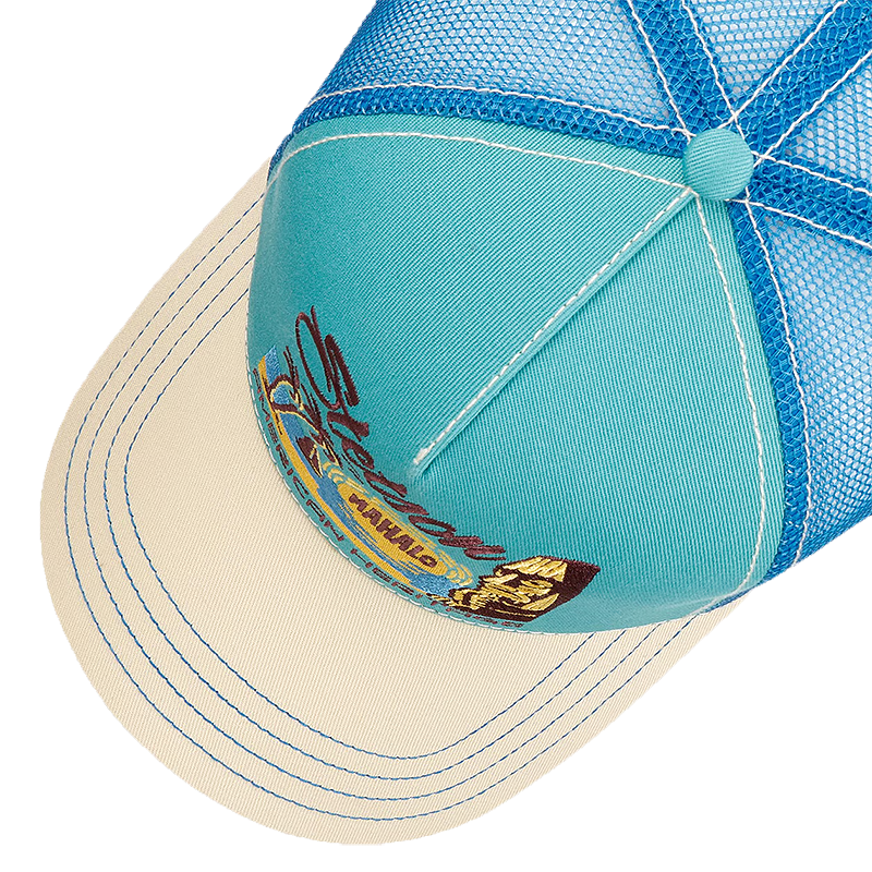 Close-up of Stetson Mahalo Trucker Cap with a turquoise front panel, blue mesh back, and cream brim with blue stitching. A small embroidered logo appears on the brim.