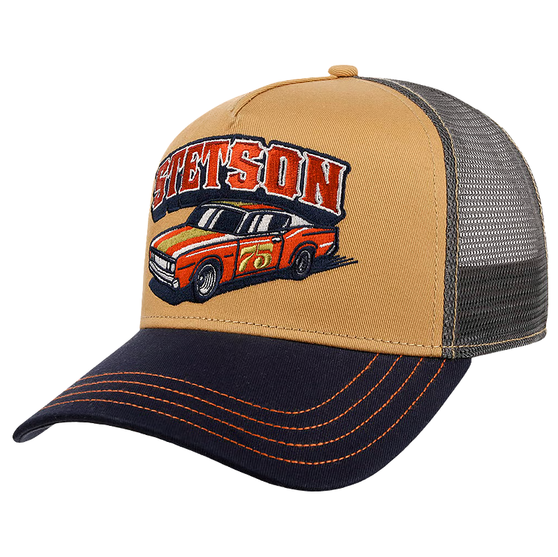 A tan and navy blue Stetson Indy Trucker Cap with a mesh back, featuring an embroidered 'SETSON' logo and a red and orange race car on the front panel.