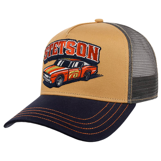 A tan and navy blue Stetson Indy Trucker Cap with a mesh back, featuring an embroidered 'SETSON' logo and a red and orange race car on the front panel.