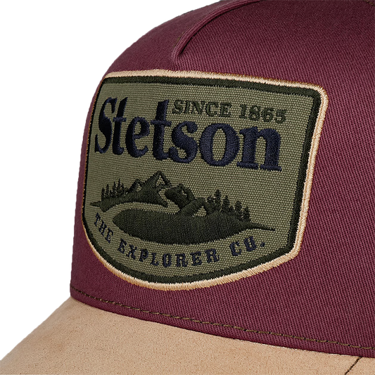 Close-up of a Stetson trucker hat featuring a burgundy crown, a tan visor, and a large embroidered Stetson patch on the front.