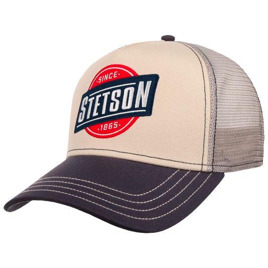 A Stetson brand trucker hat with a beige front panel, dark navy brim and embroidered logo, and a gray mesh back.